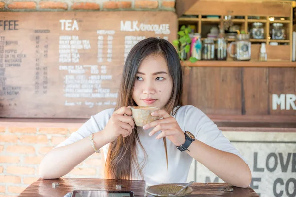 年轻的亚洲美女在木咖啡店里端着一杯热拿铁咖啡 — 图库照片