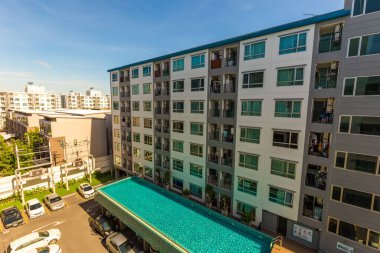 Yüzme havuzlu, mavi gökyüzü, ev ve düz konseptli modern apartman binası.