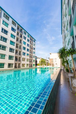 Yüzme havuzlu, mavi gökyüzü, ev ve düz konseptli modern apartman binası.