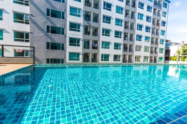 Yüzme havuzlu, mavi gökyüzü, ev ve düz konseptli modern apartman binası.