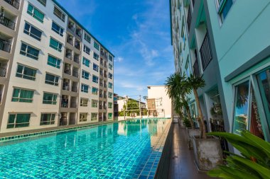 Yüzme havuzlu, mavi gökyüzü, ev ve düz konseptli modern apartman binası.