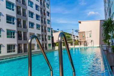 Yüzme havuzlu, mavi gökyüzü, ev ve düz konseptli modern apartman binası.