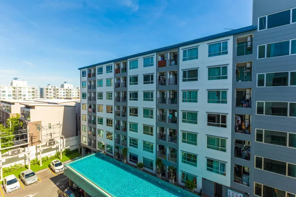 Yüzme havuzlu, mavi gökyüzü, ev ve düz konseptli modern apartman binası.