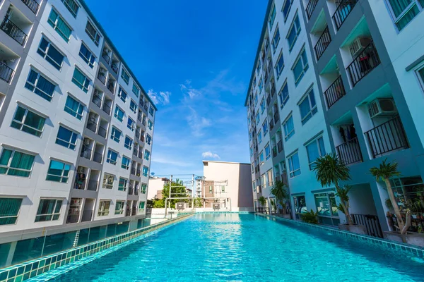 Yüzme havuzlu, mavi gökyüzü, ev ve düz konseptli modern apartman binası.