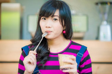 Güzel gülümseyen Asyalı kadınlar kafede oturmuş sıcak sütlü kahve içiyorlar.