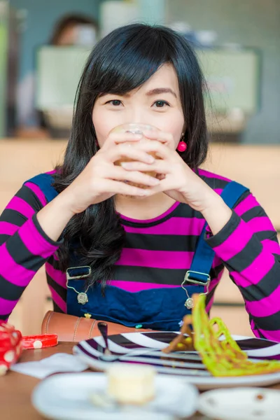 美しい笑顔アジアの女性飲む熱いラテアートコーヒーカフェに座って — ストック写真