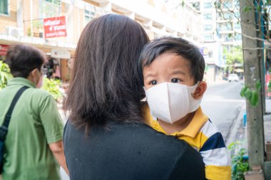 Asyalı sevimli çocuk ve anne N95 maskeli açık şehir binası Coronavirus 'u ve hava kirliliği pm2.5' i koruyor. Bilinç virüsü konsepti yaydı