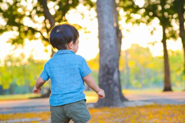 Şehir parkında oynayan sevimli küçük çocuğun portresi doğadaki bulanık arka plan çocuğu