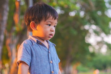 Şehir parkında oynayan sevimli küçük çocuğun portresi doğadaki bulanık arka plan çocuğu