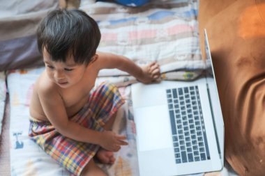 Mutlu çocuk yatak odasında dizüstü bilgisayar oynuyor ev konseptiyle çalışıyor.