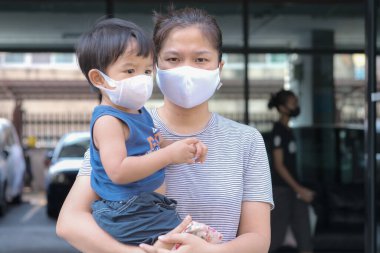 Yüzünde maske olan çocuk olan bekar bir anne. Anne ve çocuk koronavirüs ve grip salgını sırasında yüz maskesi takıyor. Virüs ve hastalık koruması