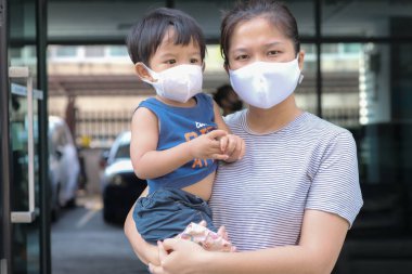 Yüzünde maske olan çocuk olan bekar bir anne. Anne ve çocuk koronavirüs ve grip salgını sırasında yüz maskesi takıyor. Virüs ve hastalık koruması