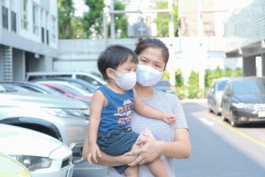 Yüzünde maske olan çocuk olan bekar bir anne. Anne ve çocuk koronavirüs ve grip salgını sırasında yüz maskesi takıyor. Virüs ve hastalık koruması