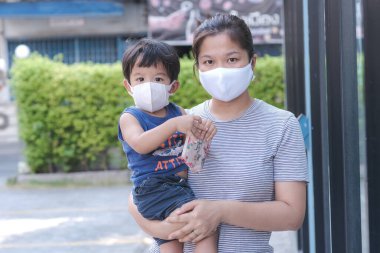 Yüzünde maske olan çocuk olan bekar bir anne. Anne ve çocuk koronavirüs ve grip salgını sırasında yüz maskesi takıyor. Virüs ve hastalık koruması