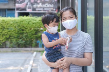 Yüzünde maske olan çocuk olan bekar bir anne. Anne ve çocuk koronavirüs ve grip salgını sırasında yüz maskesi takıyor. Virüs ve hastalık koruması