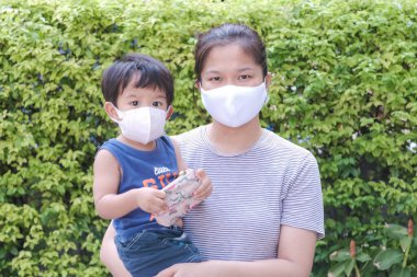 Yüzünde maske olan çocuk olan bekar bir anne. Anne ve çocuk koronavirüs ve grip salgını sırasında yüz maskesi takıyor. Virüs ve hastalık koruması