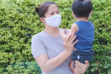 Yüzünde maske olan çocuk olan bekar bir anne. Anne ve çocuk koronavirüs ve grip salgını sırasında yüz maskesi takıyor. Virüs ve hastalık koruması