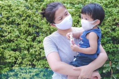 Yüzünde maske olan çocuk olan bekar bir anne. Anne ve çocuk koronavirüs ve grip salgını sırasında yüz maskesi takıyor. Virüs ve hastalık koruması