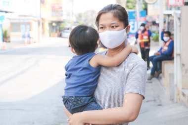 Yüzünde maske olan çocuk olan bekar bir anne. Anne ve çocuk koronavirüs ve grip salgını sırasında yüz maskesi takıyor. Virüs ve hastalık koruması