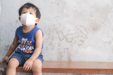 Küçük çocuk beyaz maske takıyor. PM2.5 ve CVid 19 'u koruyor. Kafede oturuyor, sağlıklı bir konsept.