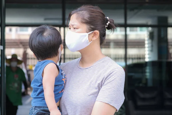Yüzünde maske olan çocuk olan bekar bir anne. Anne ve çocuk koronavirüs ve grip salgını sırasında yüz maskesi takıyor. Virüs ve hastalık koruması