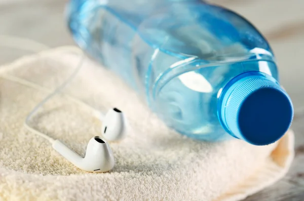 Witte koptelefoon en een fles water op een handdoek terry — Stockfoto