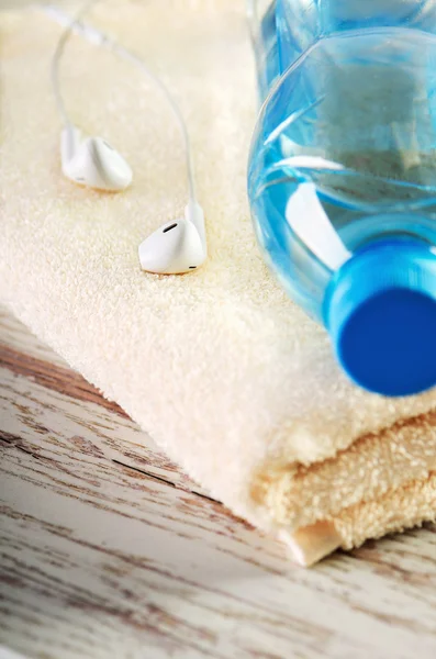Witte koptelefoon en een fles water close-up op een handdoek terry — Stockfoto
