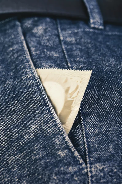 Презерватив в кармане мужских брюк крупным планом вертикальный — стоковое фото