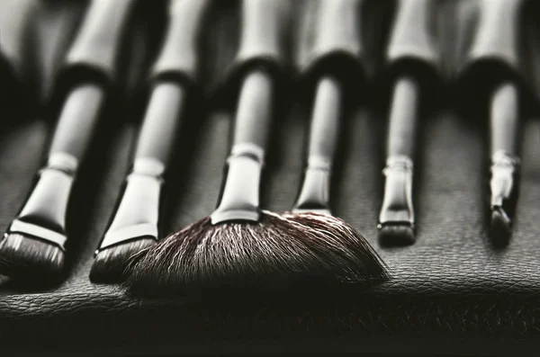 Σετ πινέλων μακιγιάζ σε ένα μαύρο κάλυμμα που τοποθετείται σε μια σειρά, fron — Φωτογραφία Αρχείου