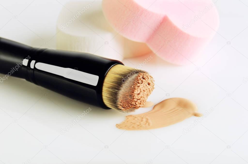 make-up brush, sponges and smear makeup base on a white backgrou
