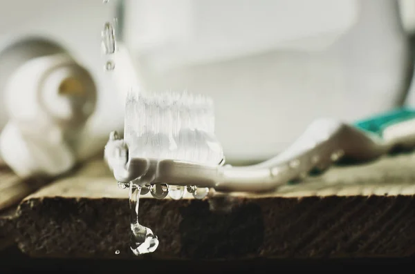 Imagen teñida cepillo de dientes húmedo en la mesa de madera. gotas de agua flo —  Fotos de Stock