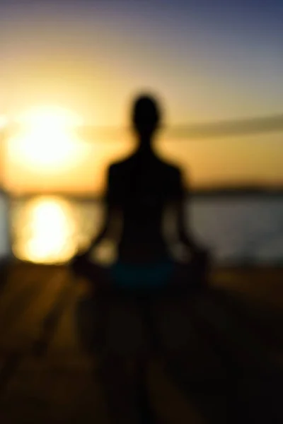 Blurred image back woman sitting in a lotus pose on the wooden p — Stock Photo, Image