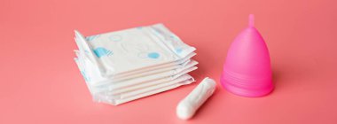 Adet bardağı ve pembe arka planda tamponlar. O dönemde alternatif kadın hijyen ürünü. Kadın sağlığı konsepti. Uzayı kopyala Çevre dostu kavram, sıfır atık ürün. Düz yatış, model, sıcaklık