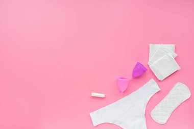 Poşetli regl kupası, hijyenik pedler, tampon, pembe arka planda beyaz külot. O dönemde alternatif kadın hijyen ürünü. Kadın sağlığı kavramı. 