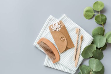 Doğal banyo aksesuarları: ahşap tarak, bambu diş fırçası, gri kağıt arka planda kulak çubukları. Sıfır atık. Model, düz yatak, şablon, üst görünüm, genel giderler