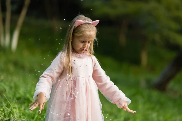 Niña con estilo con el pelo rubio lanzando confeti en el parque. Cumpleaños celebración al aire libre, diversión niño ocio —  Fotos de Stock