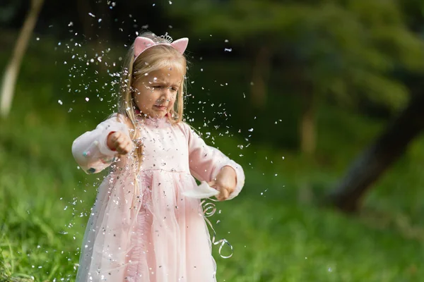 Stylish little girl with blonde hair throwing confetti in the park. Birthday celebration outdoor, fun kid leisure — Stock Photo, Image