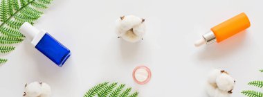 Doğal organik kozmetiklerle yatıyordu: serum, beyaz arka planda yeşil yapraklı krem. Cilt bakımı, kozmetoloji, cilt bakımı. Güzellik sertifikası, blog tarzı. Üst görünüm, üst görünüm, genel görünüm