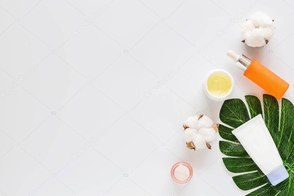 Flat lay with Natural organic cosmetics: serum, cream on white background with cotton flowers. Skincare, cosmetology, dermatology concept. Beauty certificate, blog style. Top view, mockup, overhead