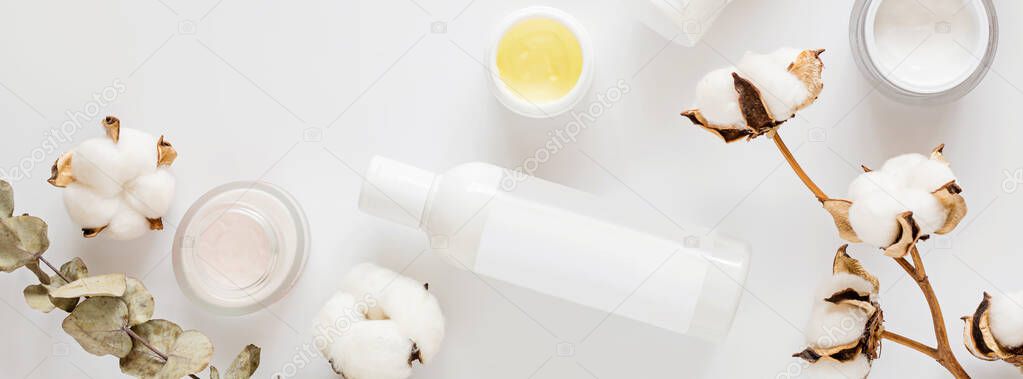 Flat lay with Natural organic cosmetics: tonic, cream on white background with cotton flowers. Skincare, cosmetology, dermatology concept. Beauty certificate, blog style. Top view, mockup, overhead