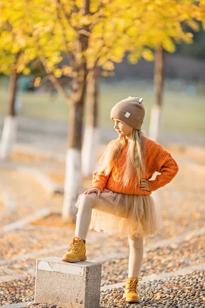 Linda niña elegante caminando en el parque de otoño con árboles de ginkgo. Moda de otoño para niños. Feliz infancia. Retrato de estilo de vida — Foto de Stock