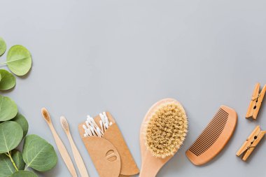Doğal banyo aksesuarları: ahşap tarak, bambu diş fırçası, masaj fırçası, gri kağıt arka planda kulak çubukları. Sıfır atık. Model, düz yatak, şablon, üst görünüm, genel giderler