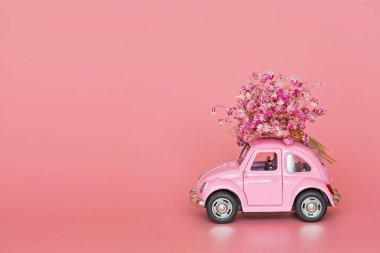 Changxing, Çin - 15 Ekim 2019: pembe arka planda çiçek buketi teslim eden pembe retro oyuncak araba. Sevgililer Günü, 14 Şubat kartı. Uluslararası Kadınlar Günü 8 Mart, Anneler Günü, Doğum günü hediyesi. C