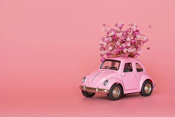 Changxing, Çin - 15 Ekim 2019: pembe arka planda çiçek buketi teslim eden pembe retro oyuncak araba. Sevgililer Günü, 14 Şubat kartı. Uluslararası Kadınlar Günü 8 Mart, Anneler Günü, Doğum günü hediyesi. C