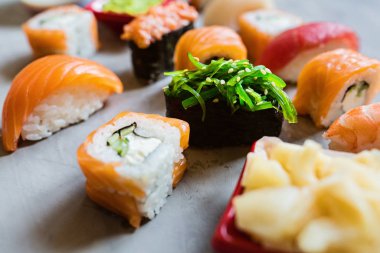 Geleneksel Japon mutfağında suşi, zencefil, soya sosu, çimento gri arka planda wasabi, dalga geç, düz yat. Çevrimiçi gıda teslimatı kavramı