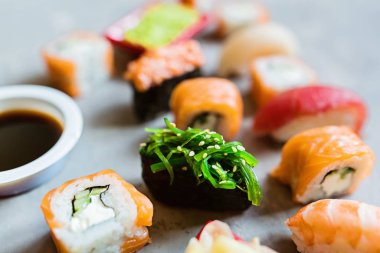 Geleneksel Japon mutfağında suşi, zencefil, soya sosu, çimento gri arka planda wasabi, dalga geç, düz yat. Çevrimiçi gıda teslimatı kavramı