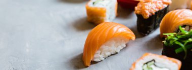 Geleneksel Japon restoranının suşi, zencefil, soya sosu, çimento grisi arka planda wasabi ile en üst görüntüsü. Çevrimiçi gıda teslimatı kavramı