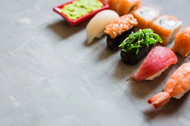 Geleneksel Japon restoranının suşi, zencefil, soya sosu, çimento grisi arka planda wasabi ile en üst görüntüsü. Çevrimiçi gıda teslimatı kavramı