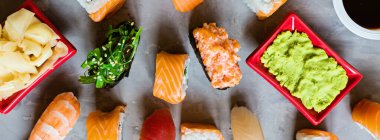 Geleneksel Japon restoranının suşi, zencefil, soya sosu, çimento grisi arka planda wasabi ile en üst görüntüsü. Çevrimiçi gıda teslimatı kavramı