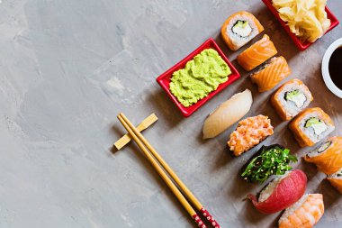 Geleneksel Japon restoranının suşi, zencefil, soya sosu, çimento grisi arka planda wasabi ile en üst görüntüsü. Çevrimiçi gıda teslimatı kavramı